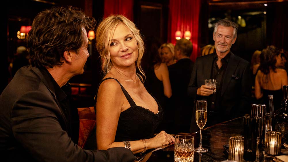 Femme mature flirtant sous le regard de son mari dans un club libertin